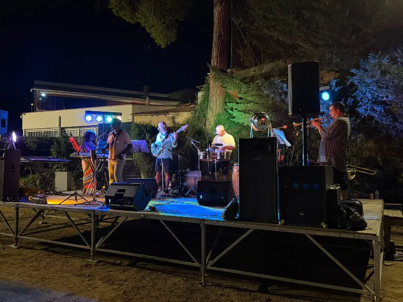 Arturito & La Máquina del Sabor tocando salsa en directo en un escenario al aire libre de noche en Barcelona